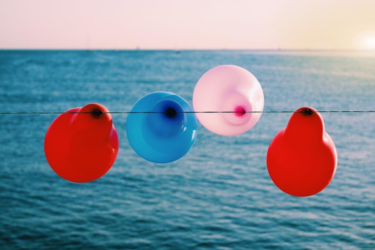 4 balloons on a sting near the ocean